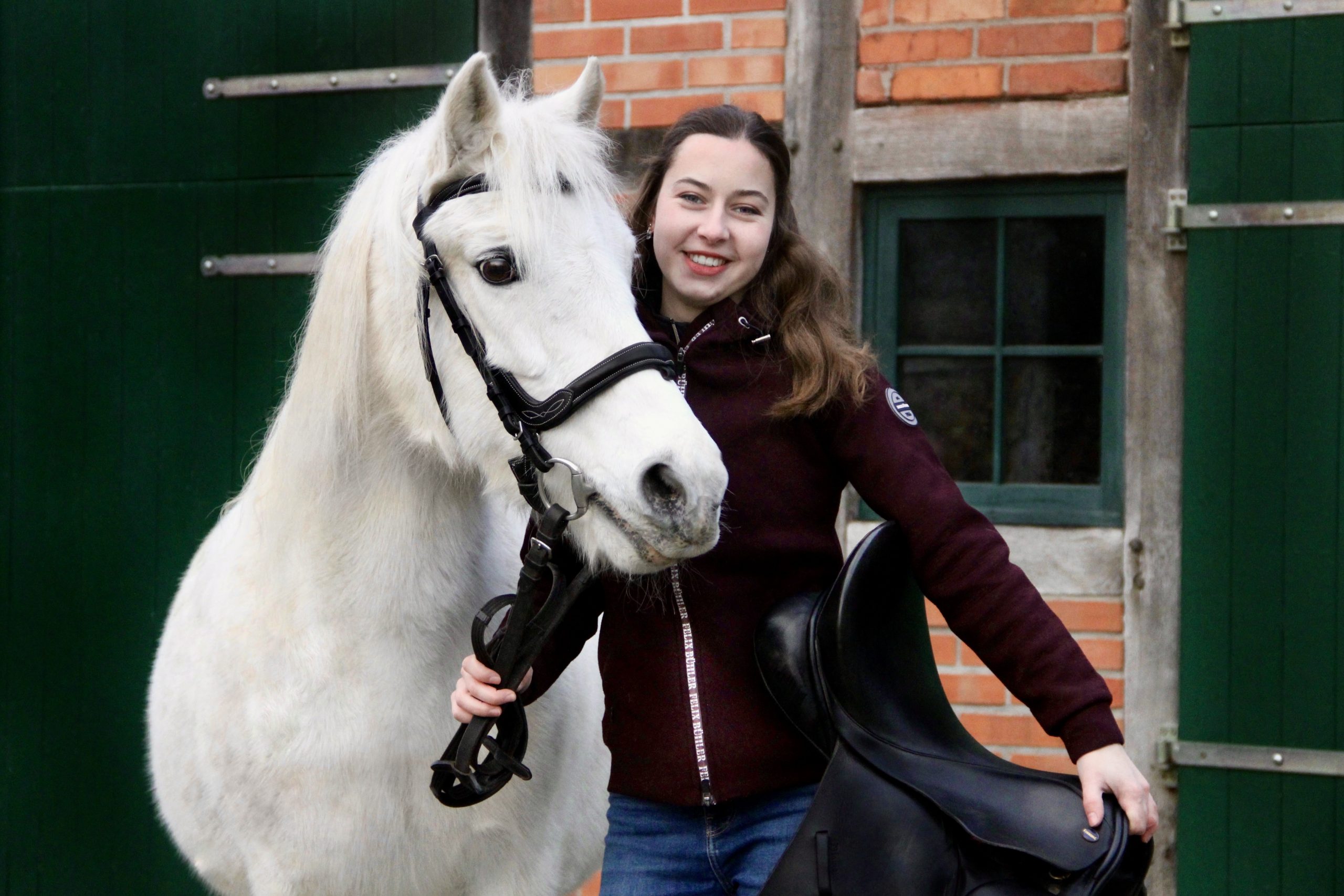 Pferd Kira mit Sattlerin Johanna Sowa und Sattel in der Hand